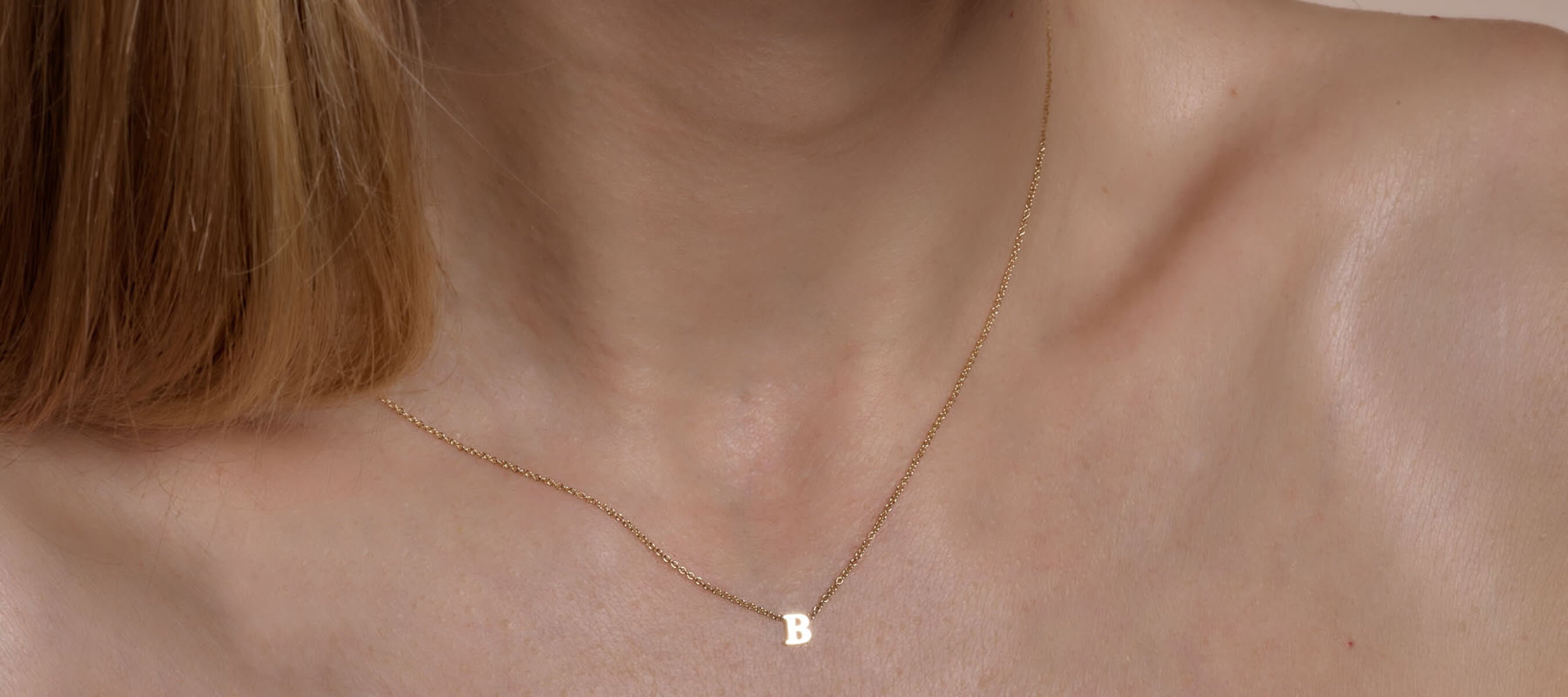 Female model with wearing letter B gold initial necklace.
