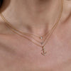 Layered gold diamond rectangle, 1-letter initial, and diamond anchor necklaces on neck