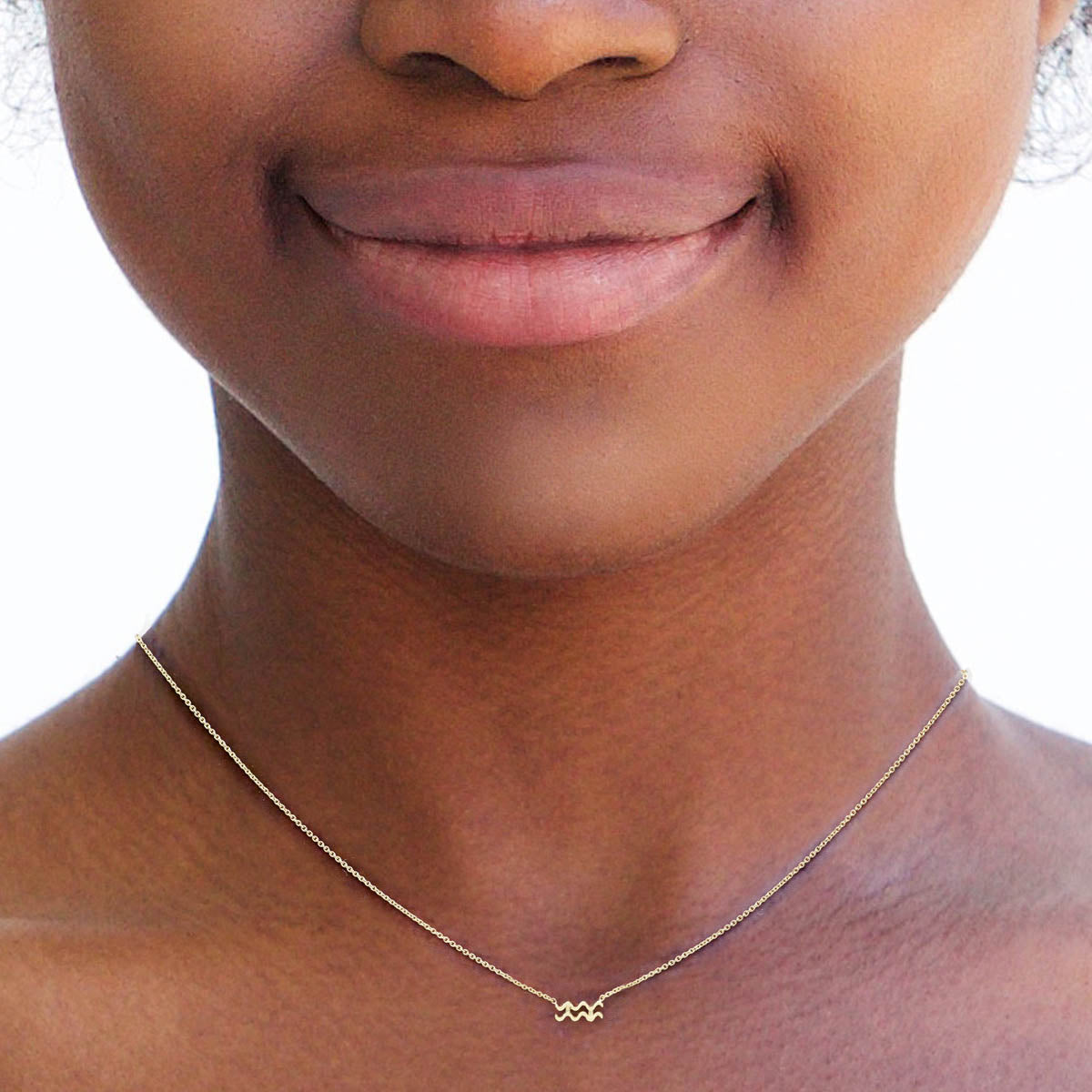 Aquarius gold zodiac necklace on a woman's neck by Phoenix Roze