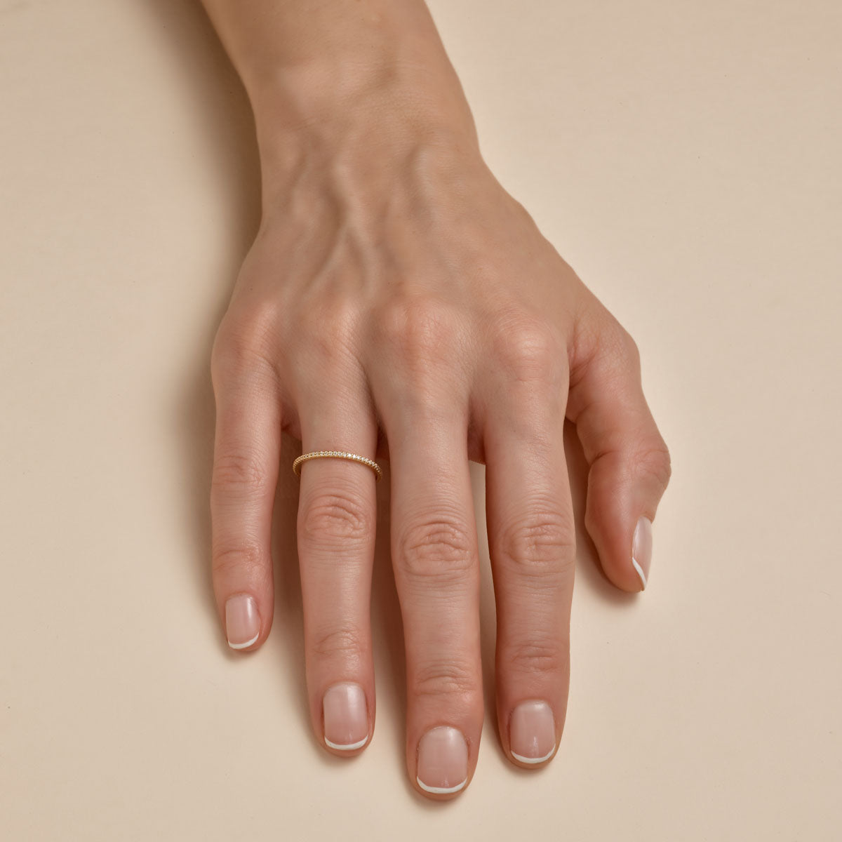 Channel-set white diamond eternity band ring on woman's finger by Phoenix Roze