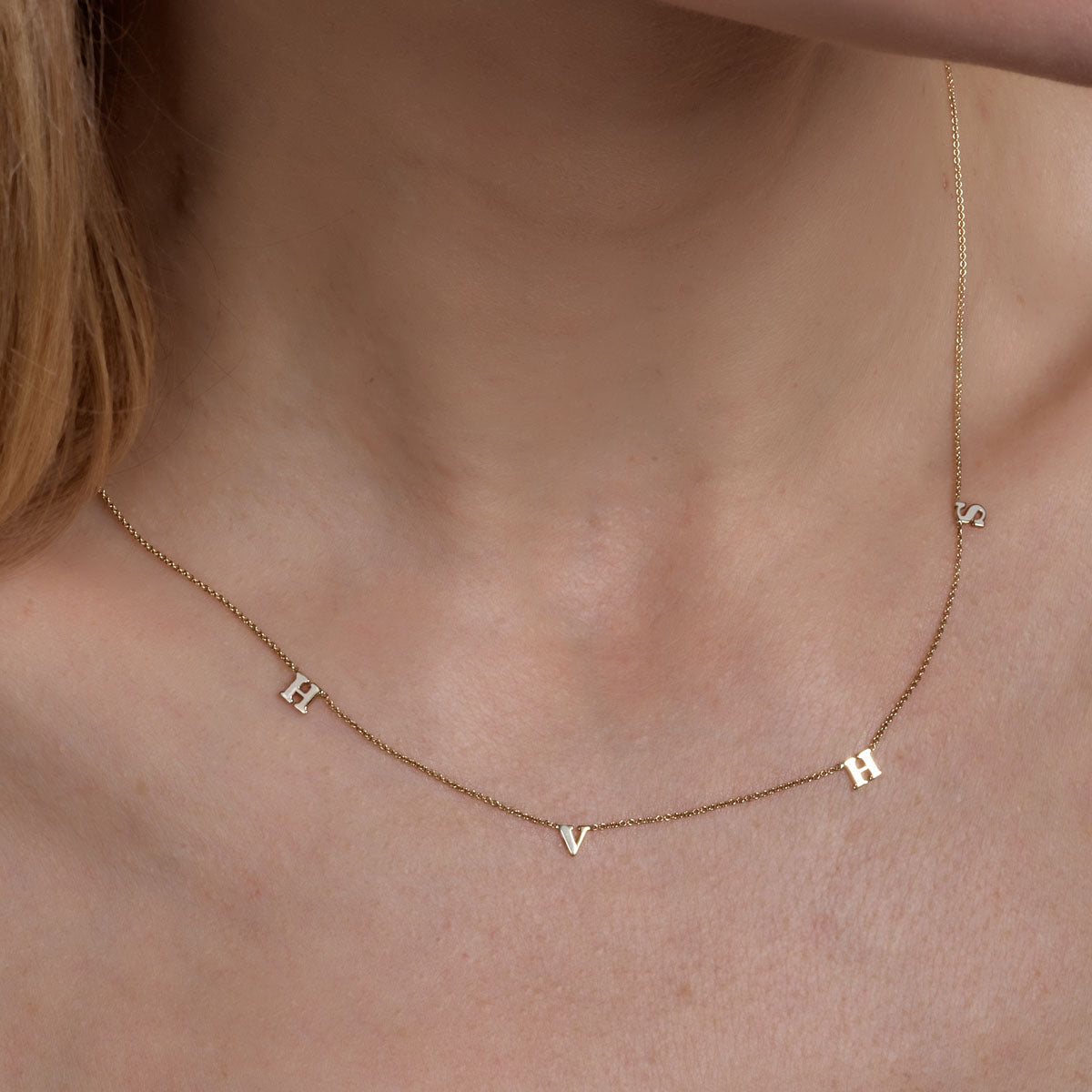 Gold 4-letter initial necklace on a woman's neck, personalized custom monogram jewelry