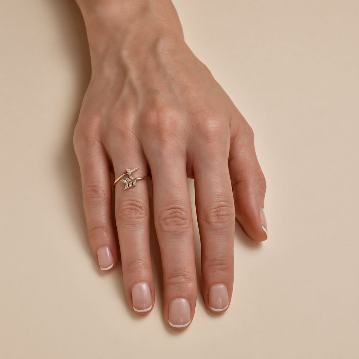 Close-up of a gold arrow ring on a woman's finger, dainty minimalist stackable jewelry