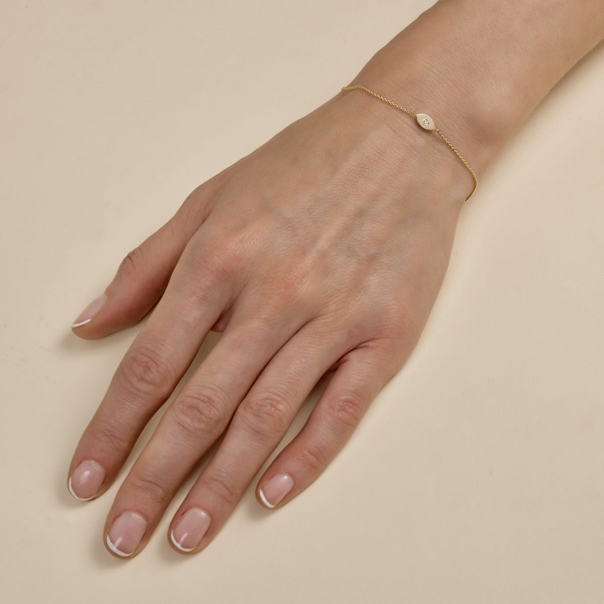 Gold diamond evil eye bracelet on woman's hand, delicate Phoenix Roze jewelry for protection and sparkle.