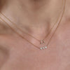 Gold diamond Libra necklace and gold diamond triple heart necklace layered on neck, delicate sparkle.