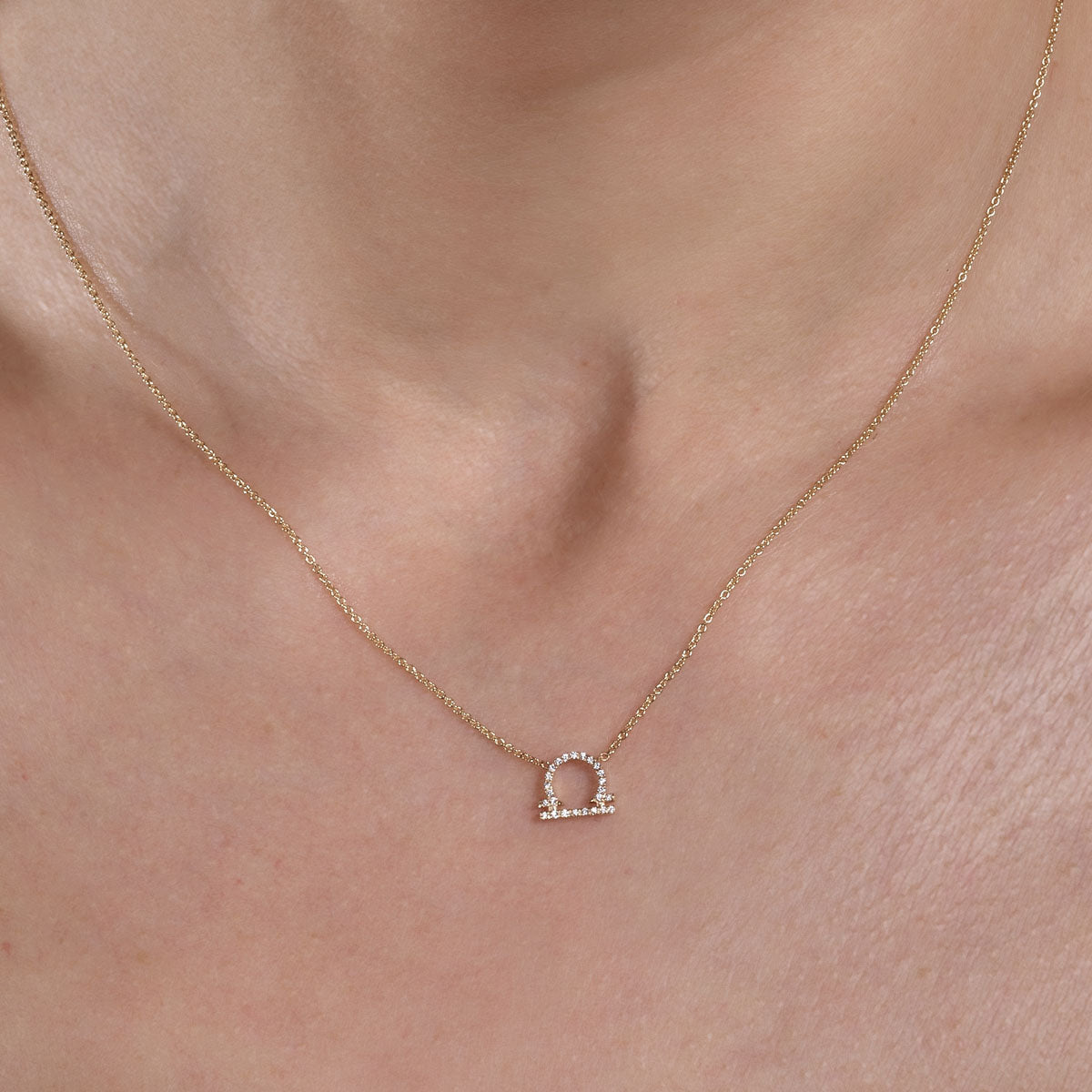 Elegant gold diamond Libra necklace on a woman's neck, sparkling zodiac pendant close-up