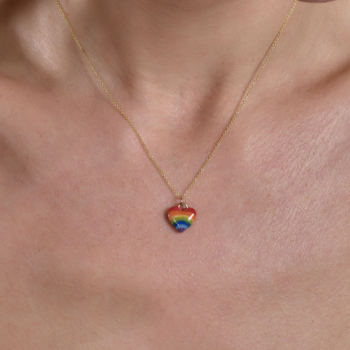 Model wearing gold rainbow heart necklace on neck, delicate heart pendant with multicolor gems by Phoenix Roze