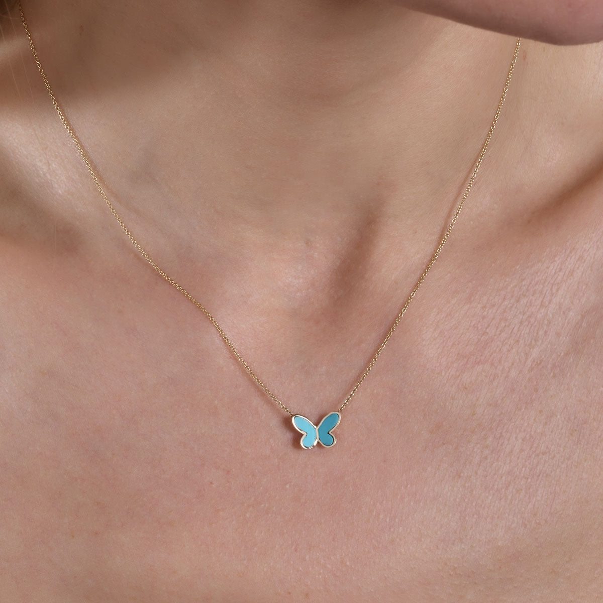 gold turquoise butterfly necklace on models neck