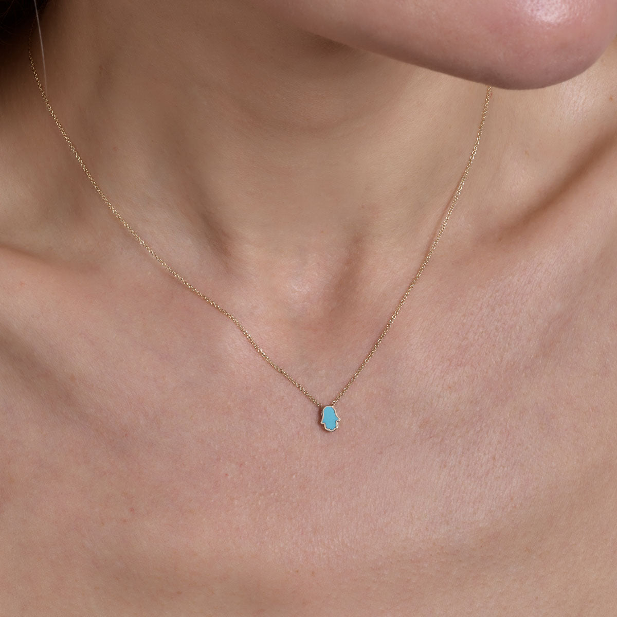 Phoenix Roze gold and turquoise Hamsa necklace on model's neck, delicate 14k charm pendant.