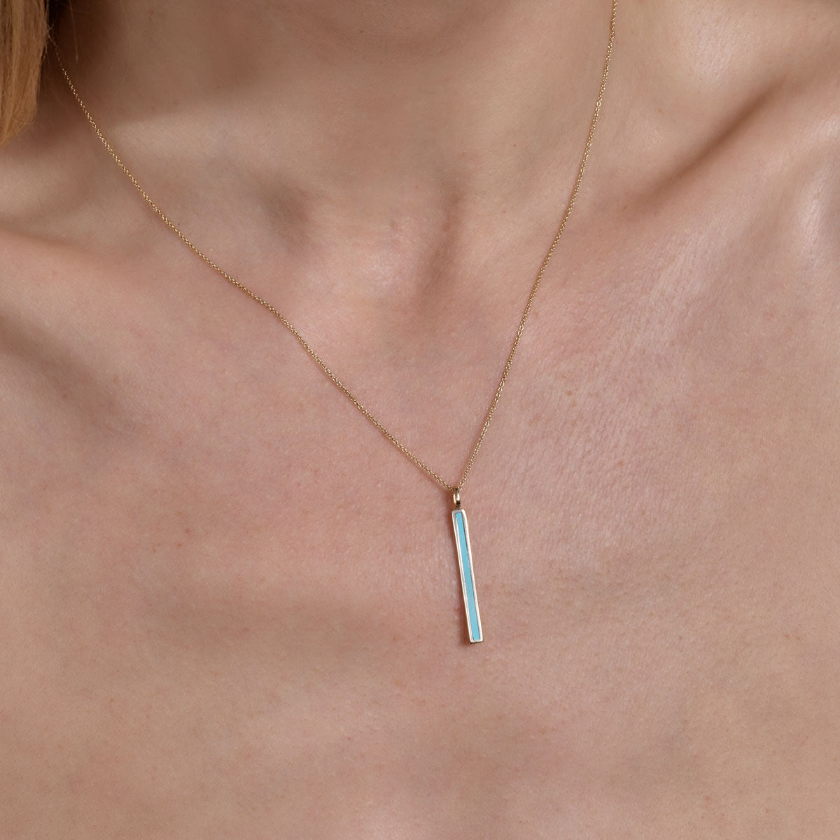 gold turquoise long bar necklace on models neck