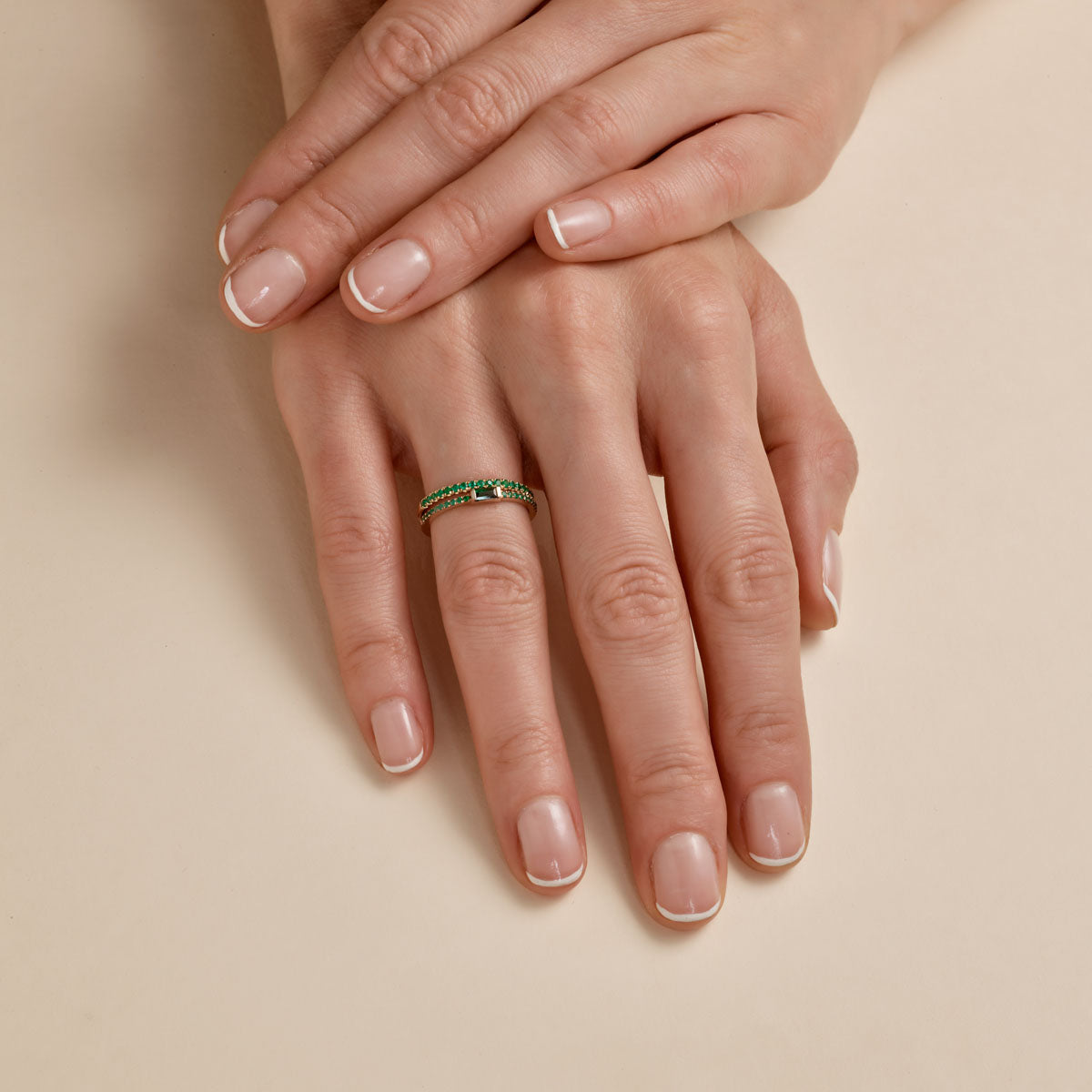 Close-up of multiple emerald baguette ring on woman's finger, sleek green gemstone band for modern elegance by Phoenix Roze