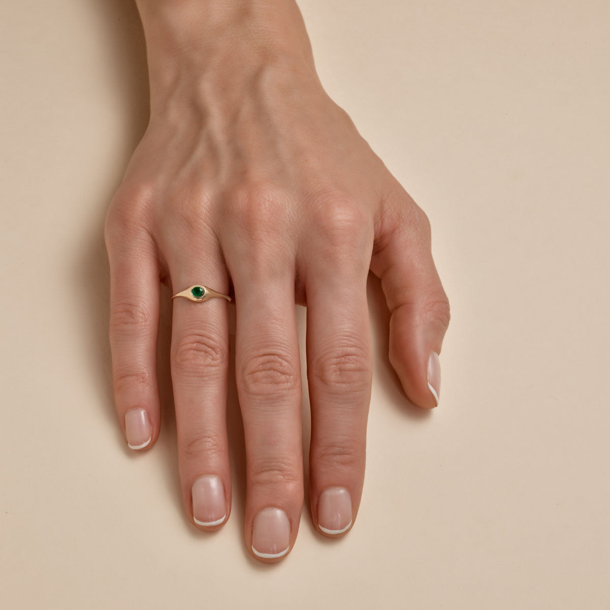 Small oval emerald signet ring on woman's finger – dainty gold ring, elegant gemstone jewelry by Phoenix Roze.