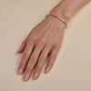 Solid gold hinged bangle bracelet on a woman's hand, sleek minimalist fine jewelry by Phoenix Roze