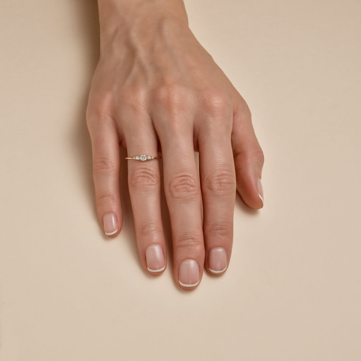 Tiny five diamond crown ring on woman's hand, delicate gold stacking ring by Phoenix Roze.