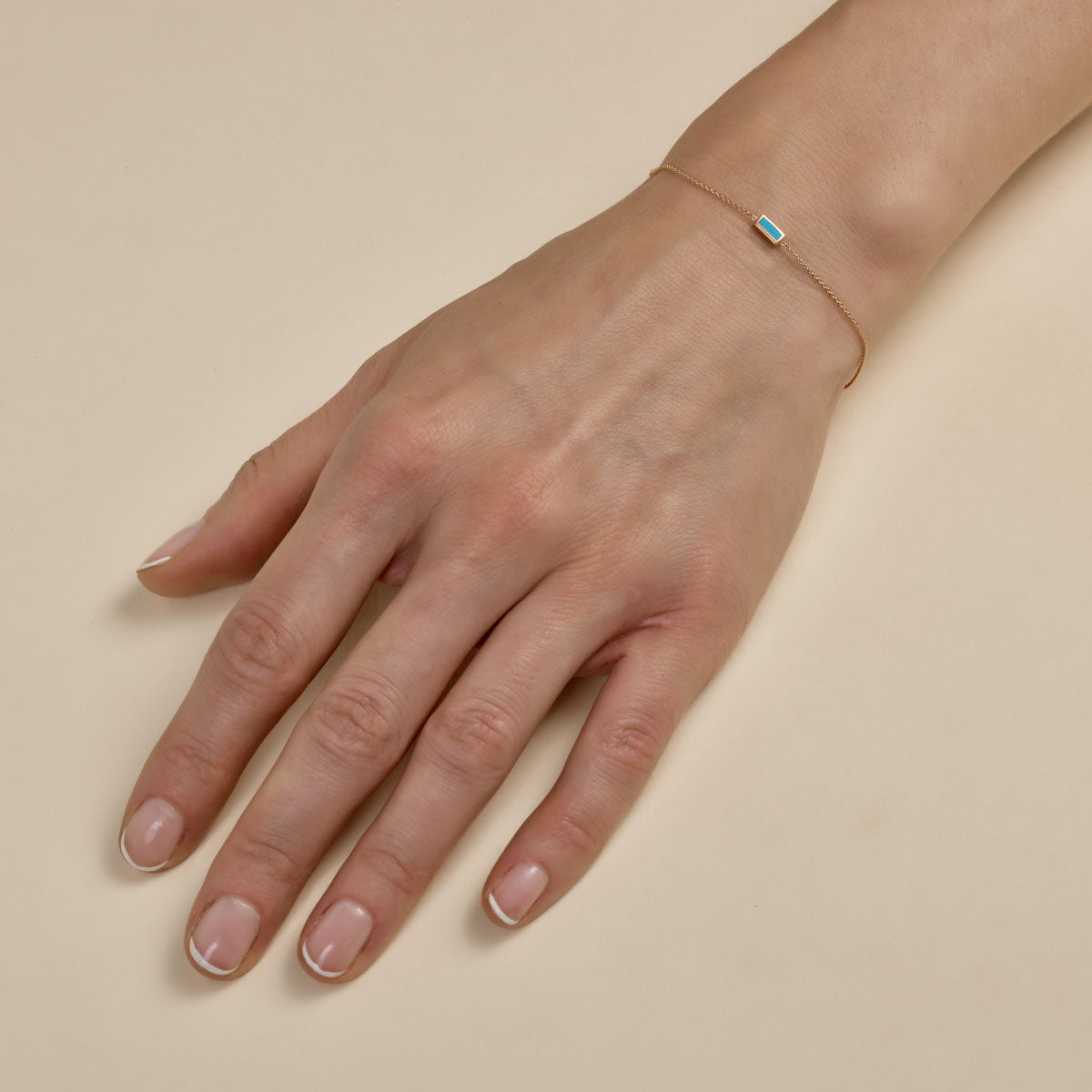Tiny inlay rectangle turquoise bar gold bracelet on woman's hand, delicate minimalist jewelry