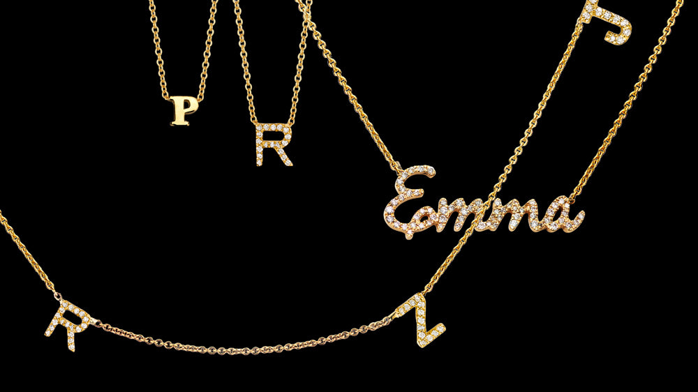 Gold initial letter necklaces layered with a diamond script name necklace spelling Emma
