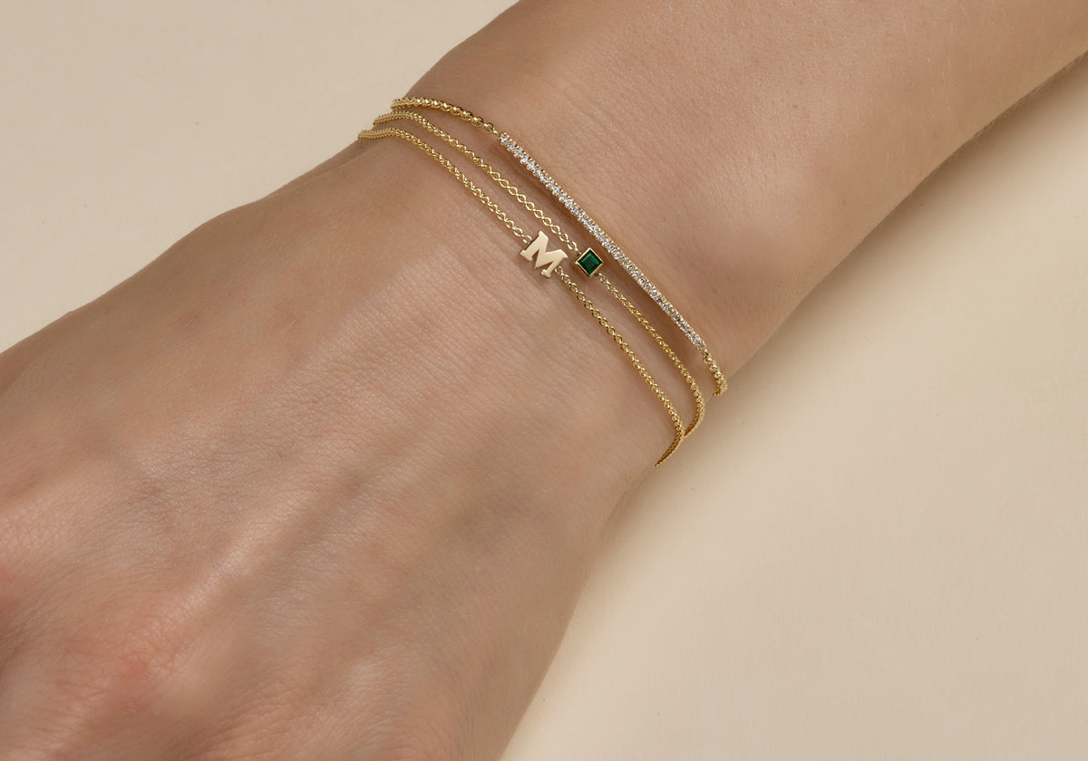 Model wearing 3 differend gold bracelets on wrist.
