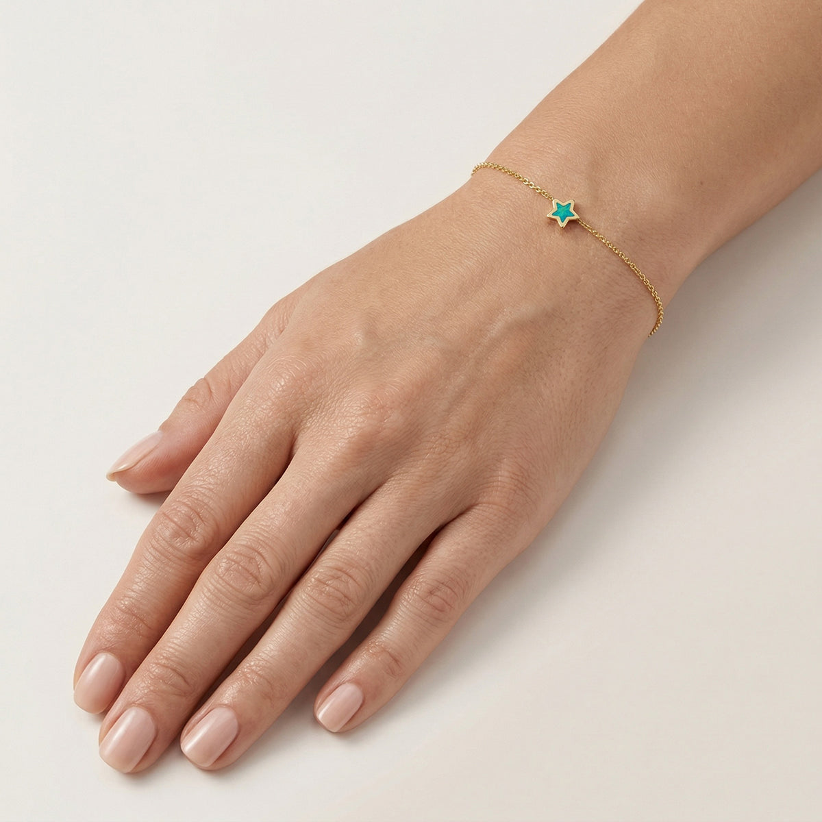 14k yellow gold opal star bracelet worn on model's wrist showing scale and fit