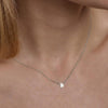 A woman wearing a delicate silver chain necklace featuring a central, single letter B pendant.