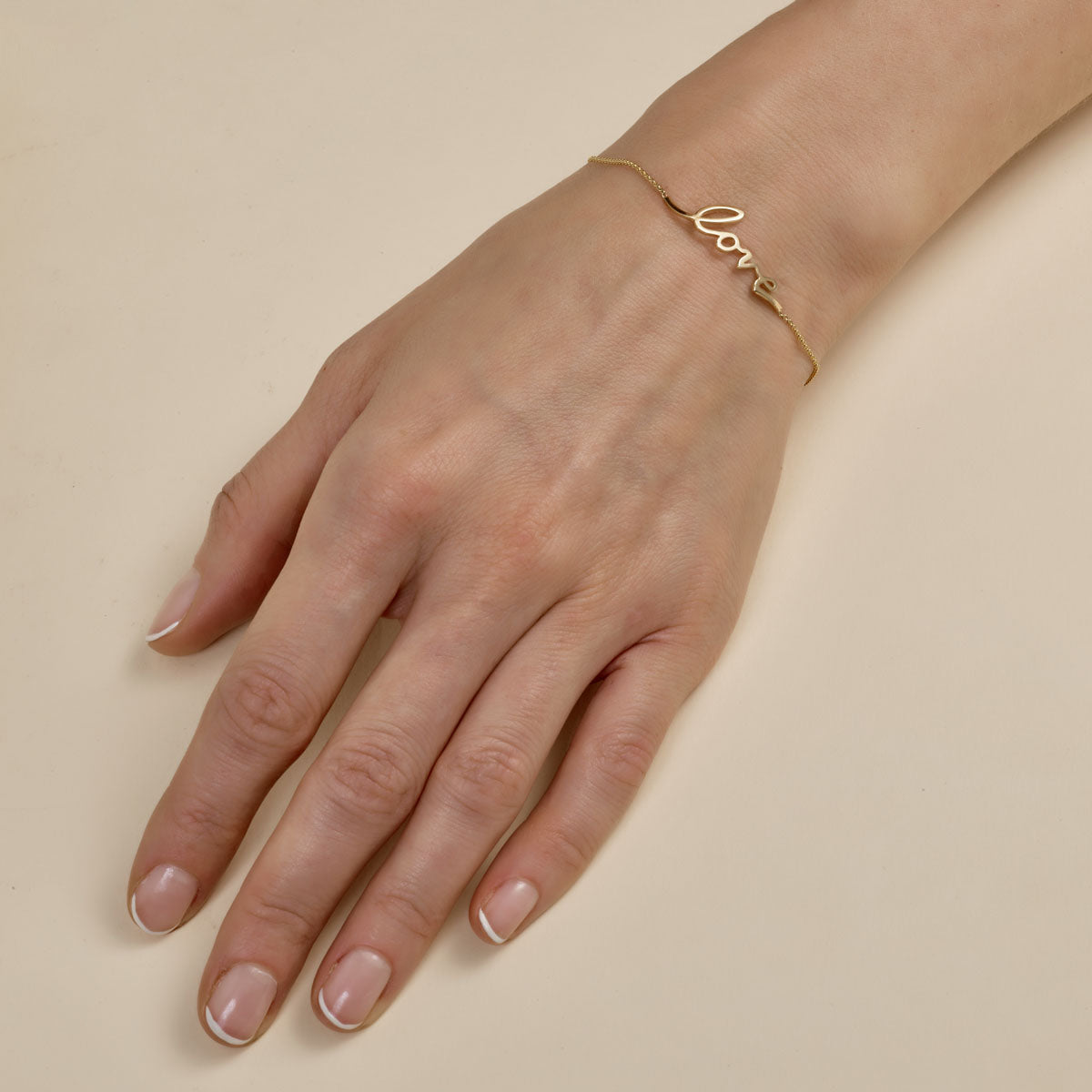 cursive gold love bracelet on womans wrist