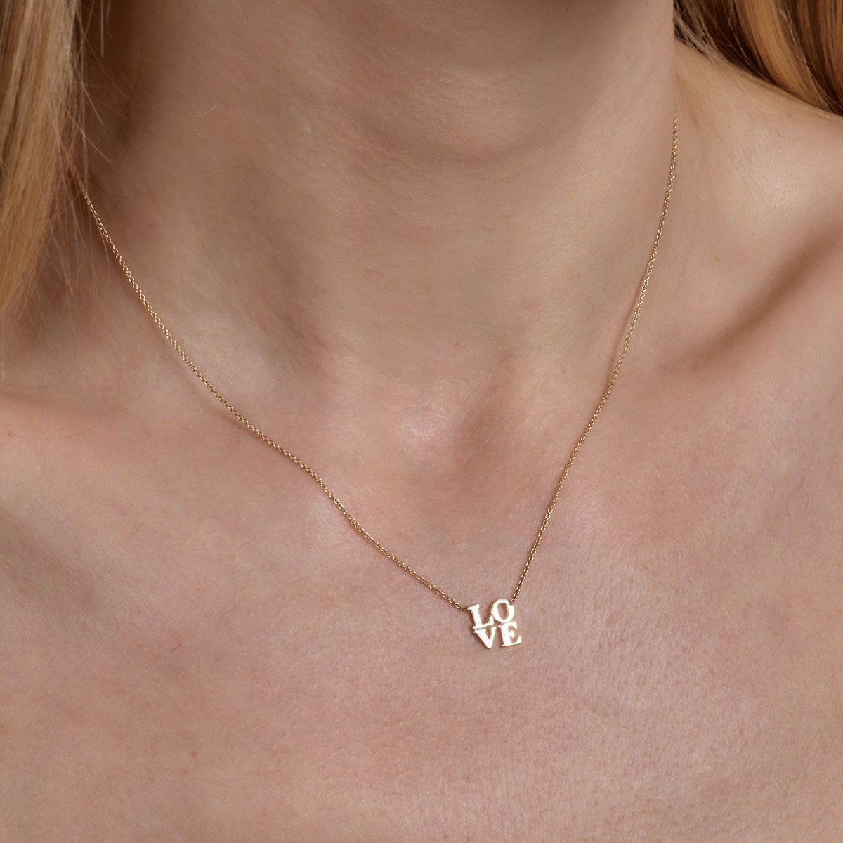 gold LOVE necklace on womans neck