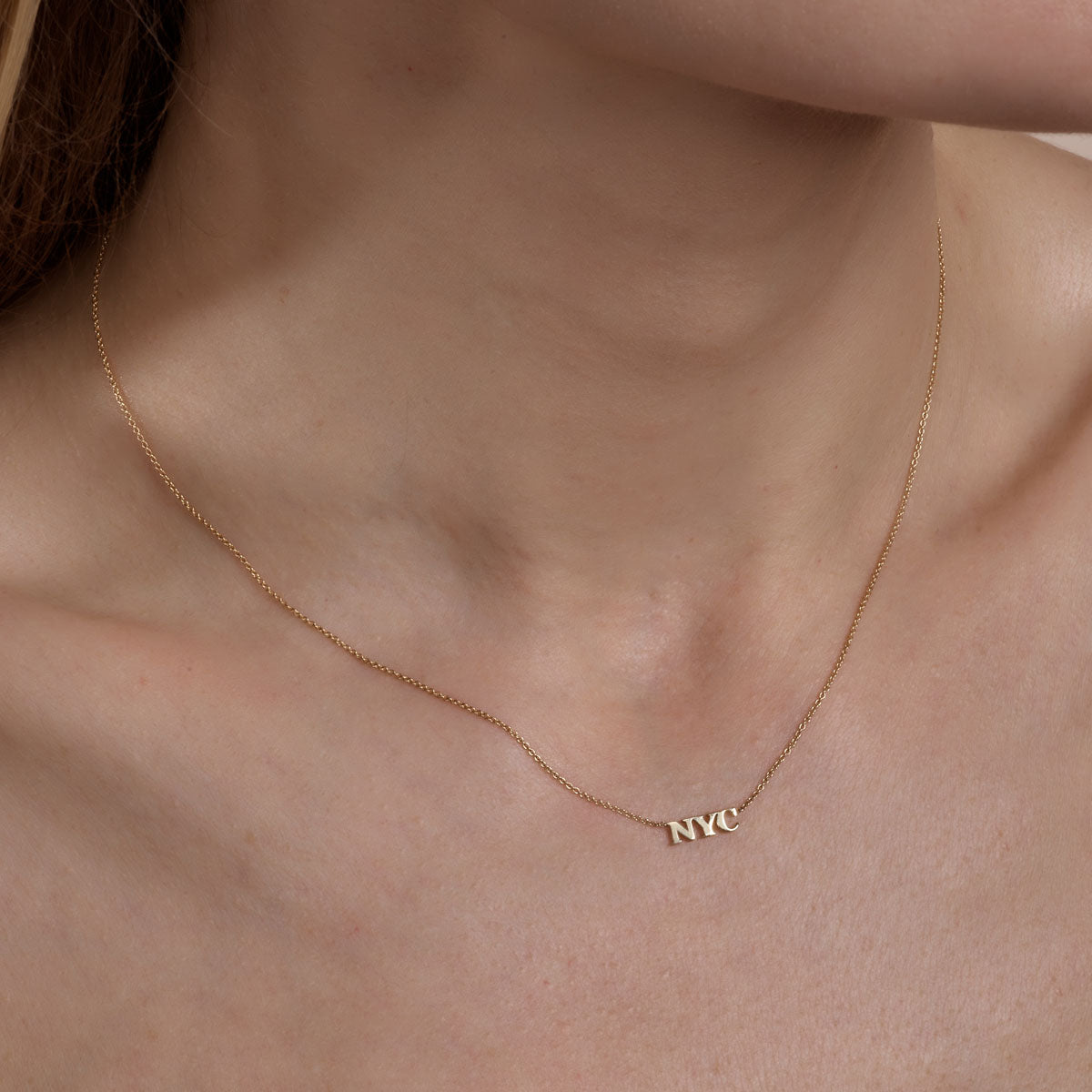 gold NYC necklace on womans neck