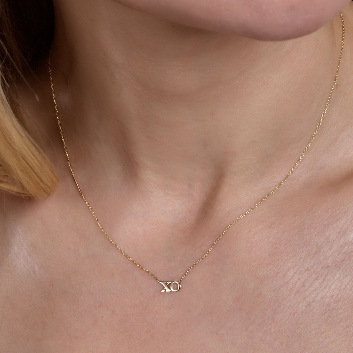 gold XO necklace on womans neck