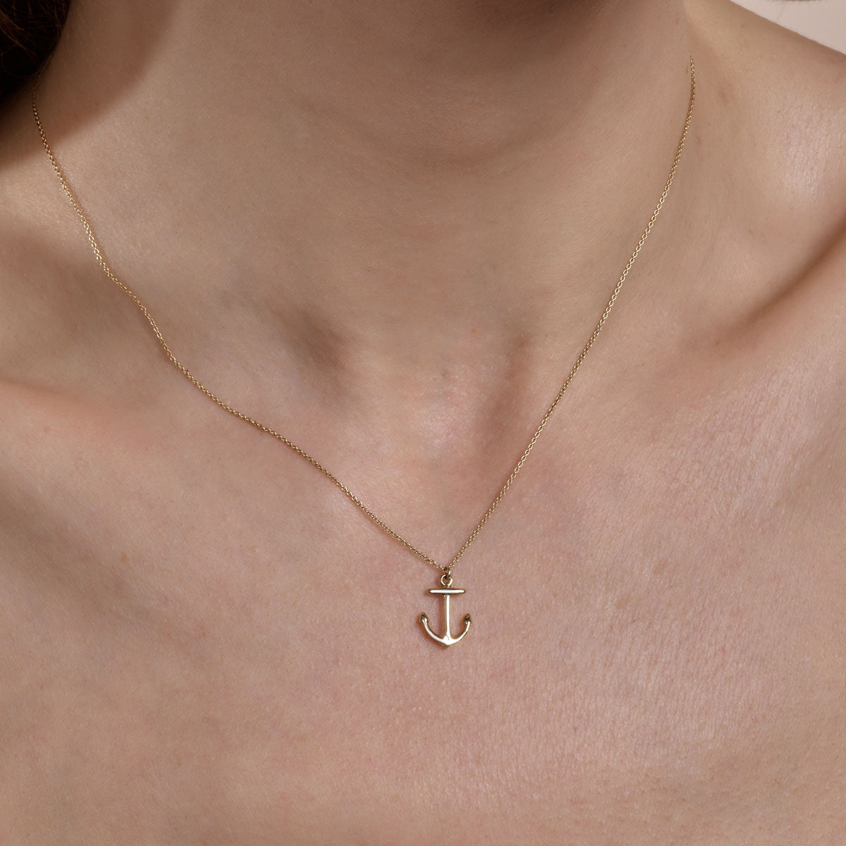 gold anchor necklace on womans neck