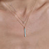 Model wearing gold diamond initial and turquoise bar necklaces, showcasing sophistication & style.