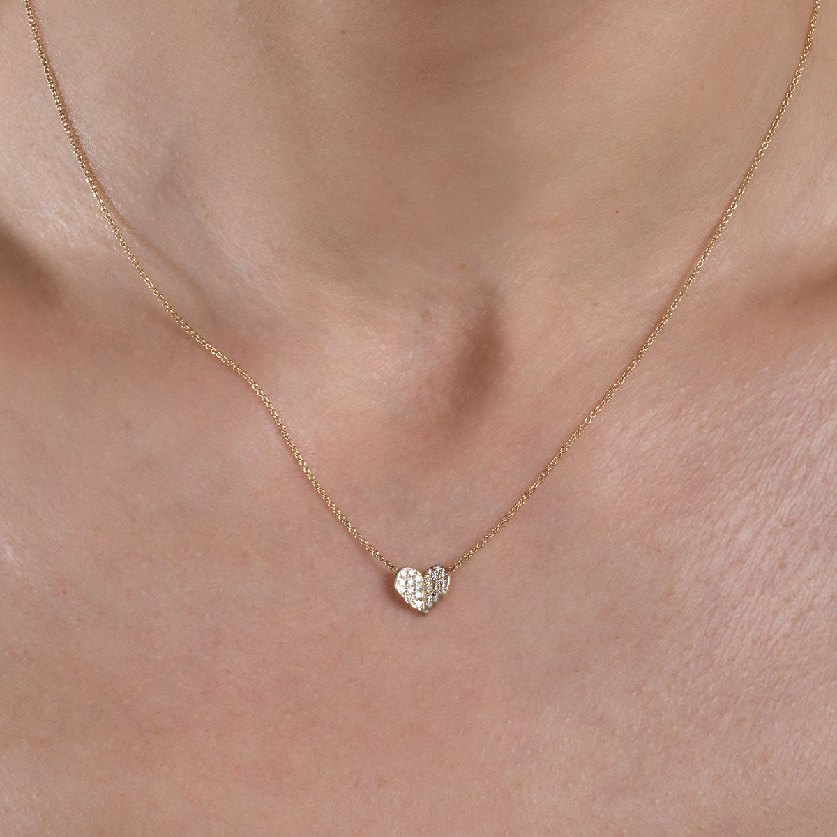 gold diamond heart necklace on models neck