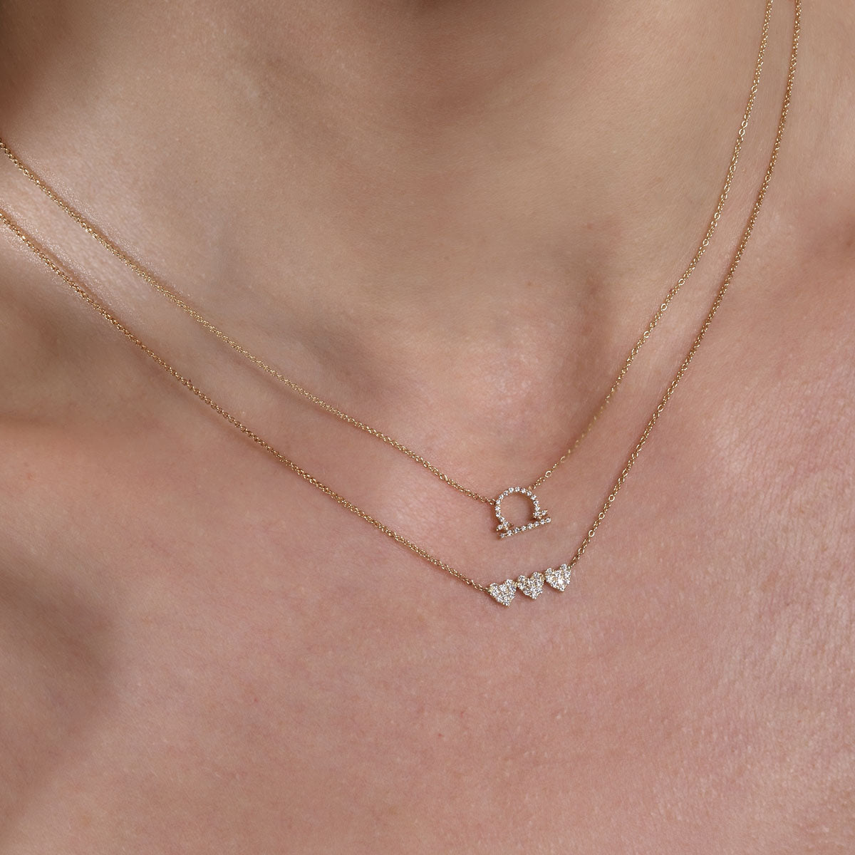 gold diamond libra necklace and gold diamond triple heart necklace on neck