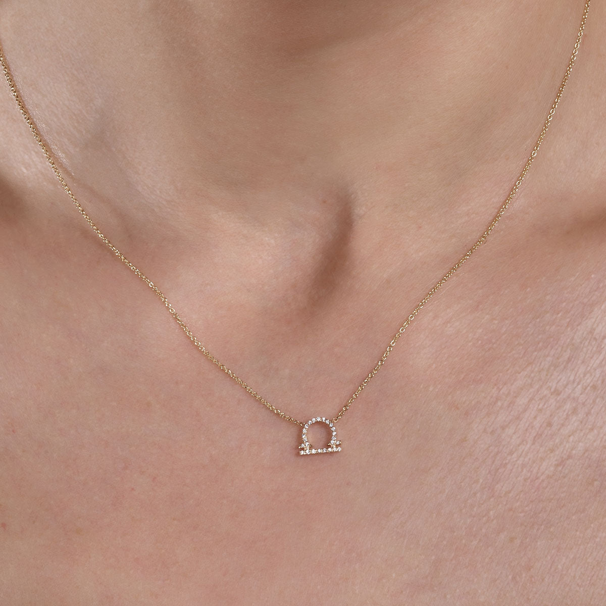 gold diamond libra necklace on womans neck
