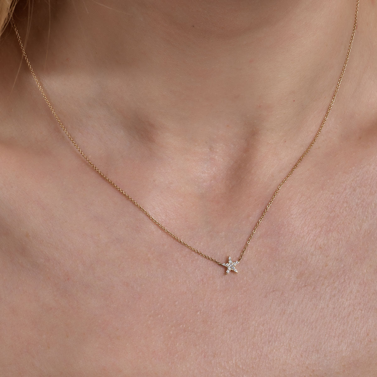 gold diamond star necklace on womans neck