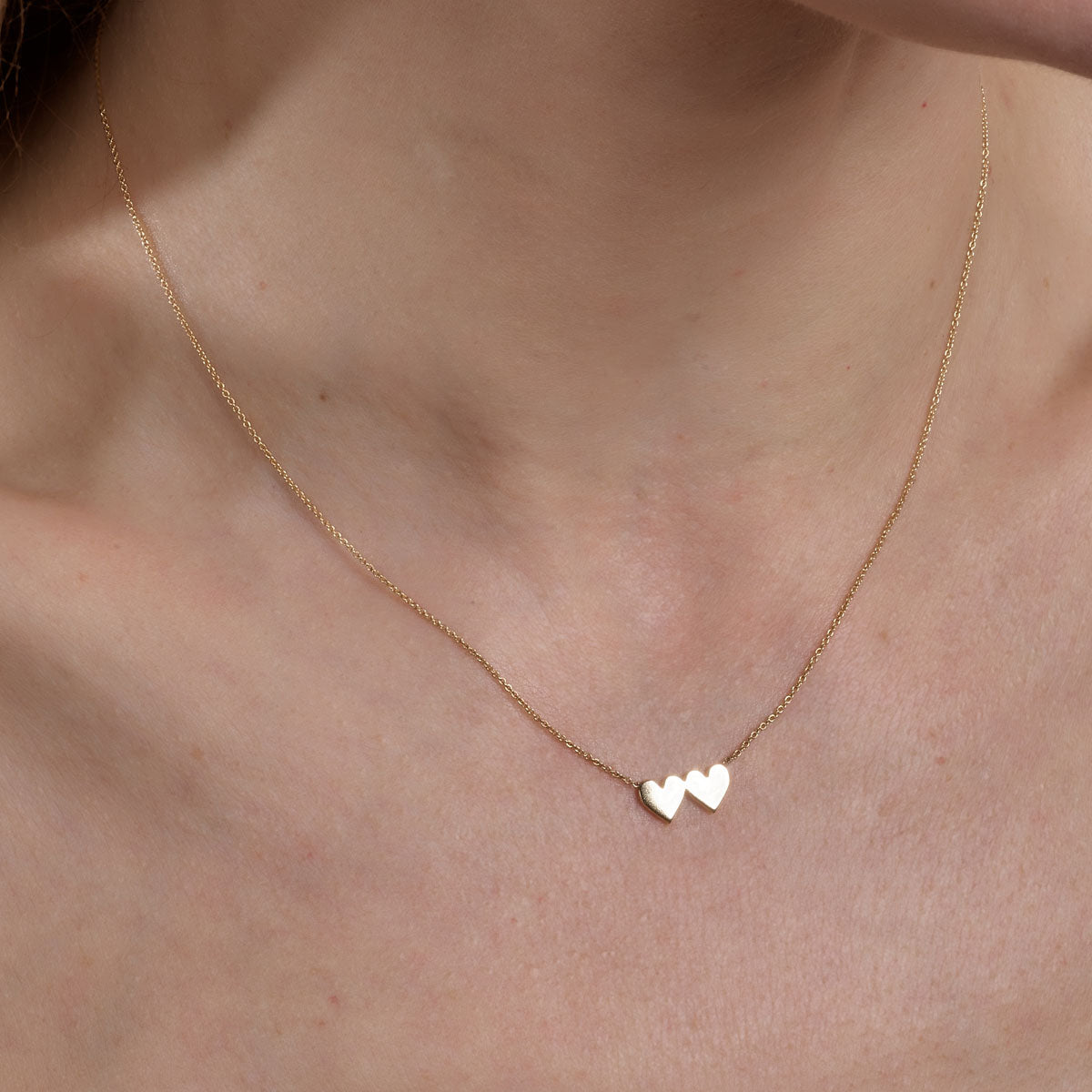 gold double heart necklace on womans neck