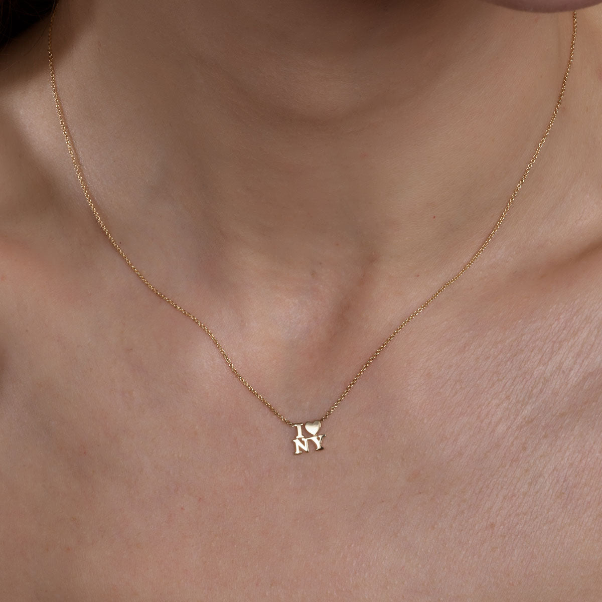 gold i heart NY necklace on womans neck
