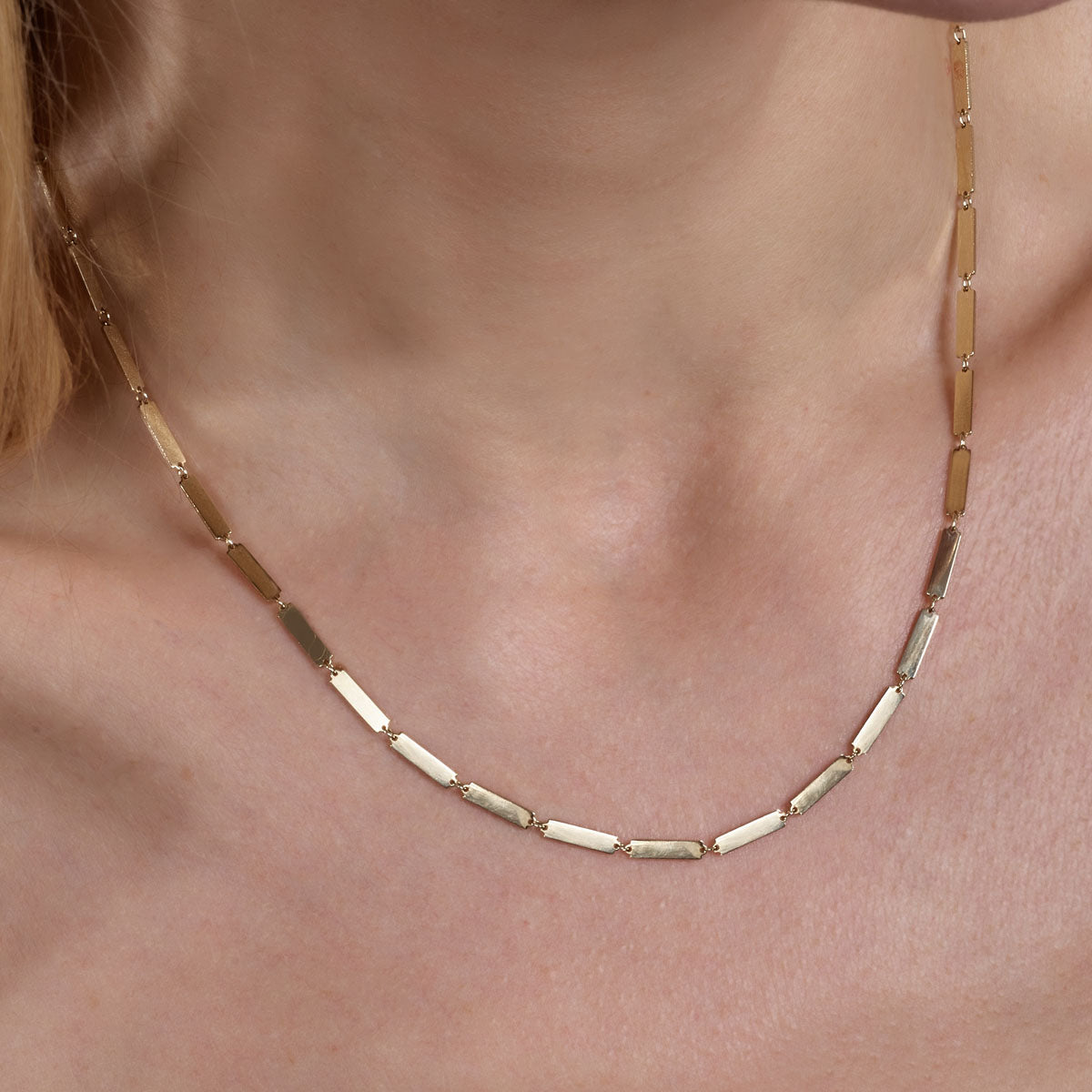 gold long bar links necklace on models neck