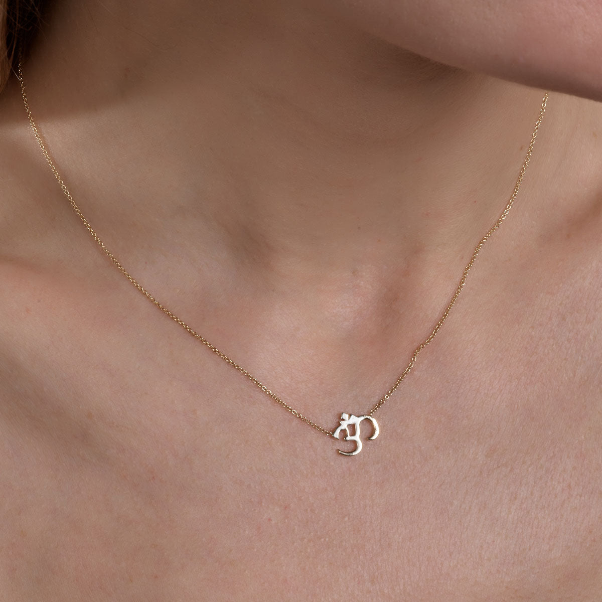 gold om necklace on womans neck