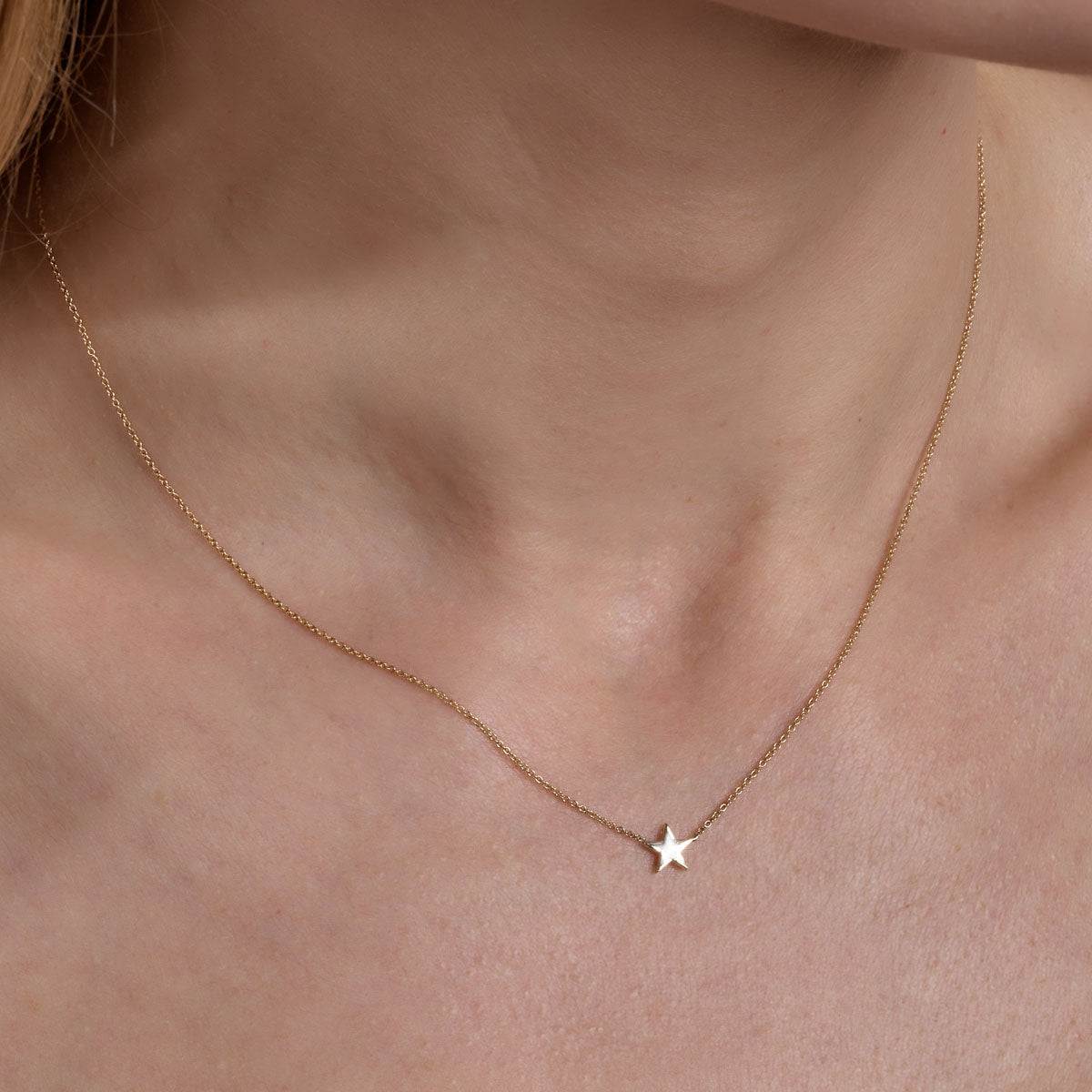 gold star necklace on womans neck