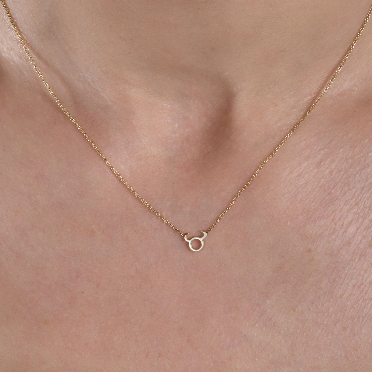 gold taurus necklace on womans neck