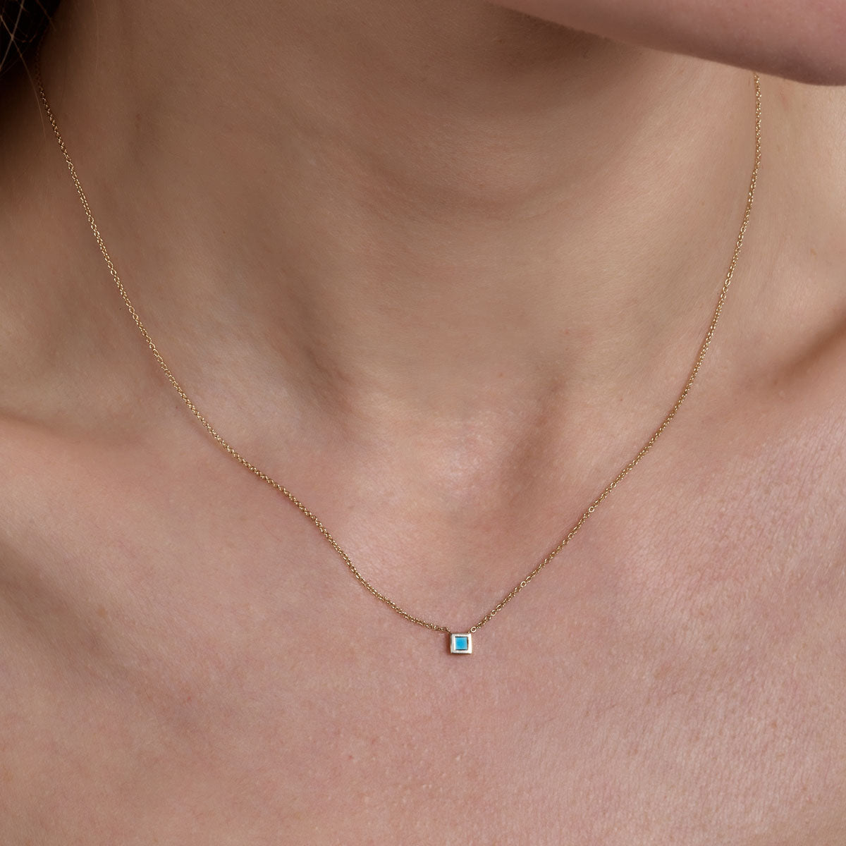 gold turquoise square necklace on models neck