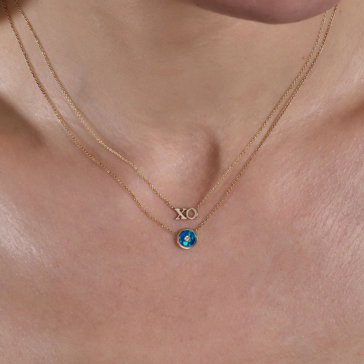 gold xo necklace and gold turquoise blue round necklace on neck