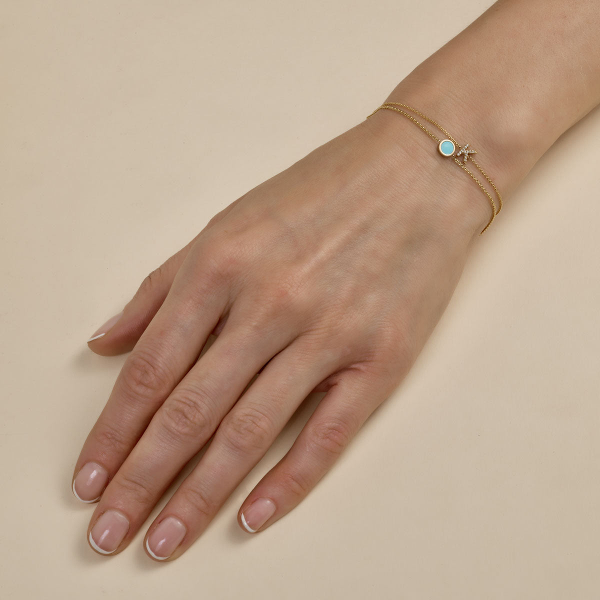 multiple gold and initial bracelets stacked on womans hand