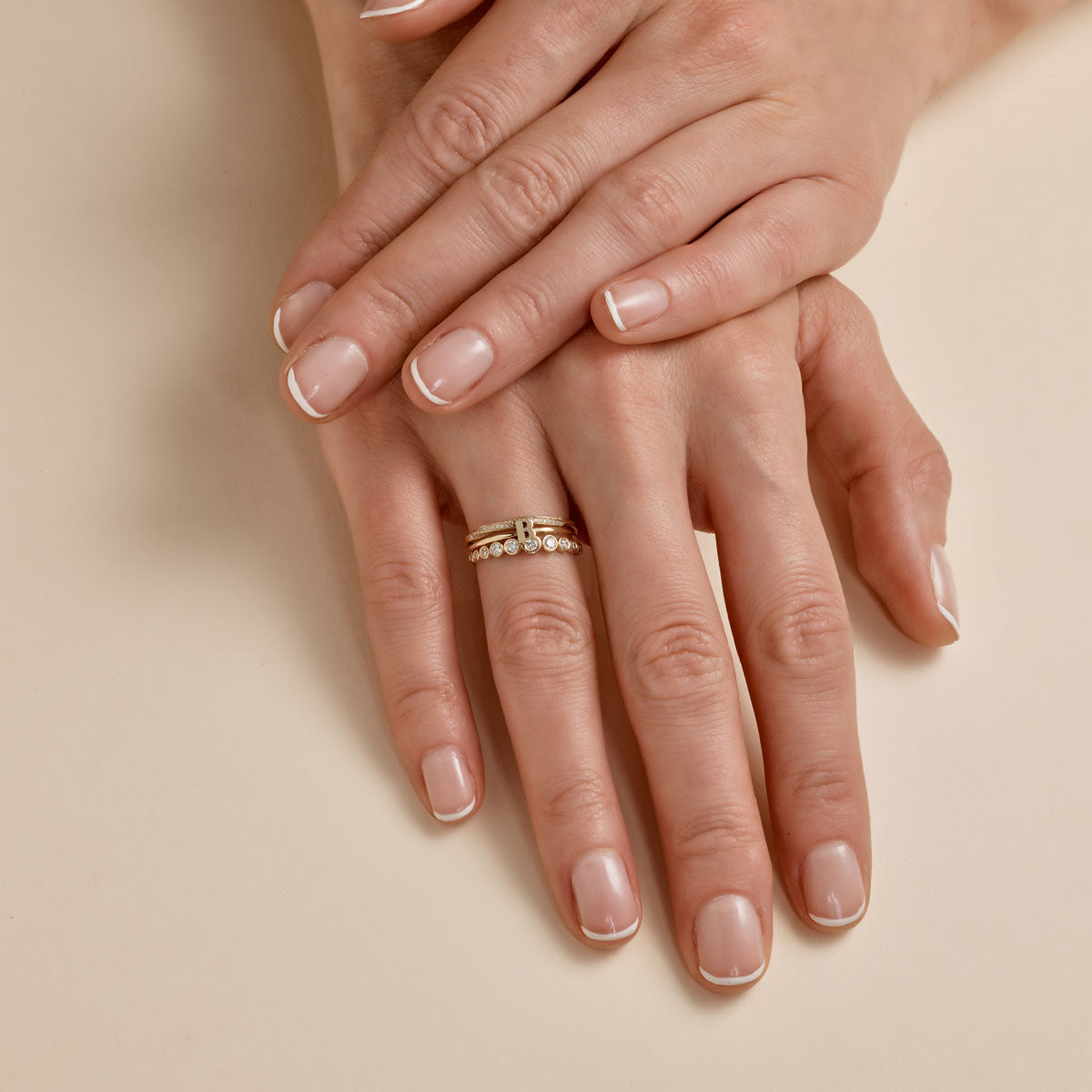 multiple gold and initial rings stacked on womans finger