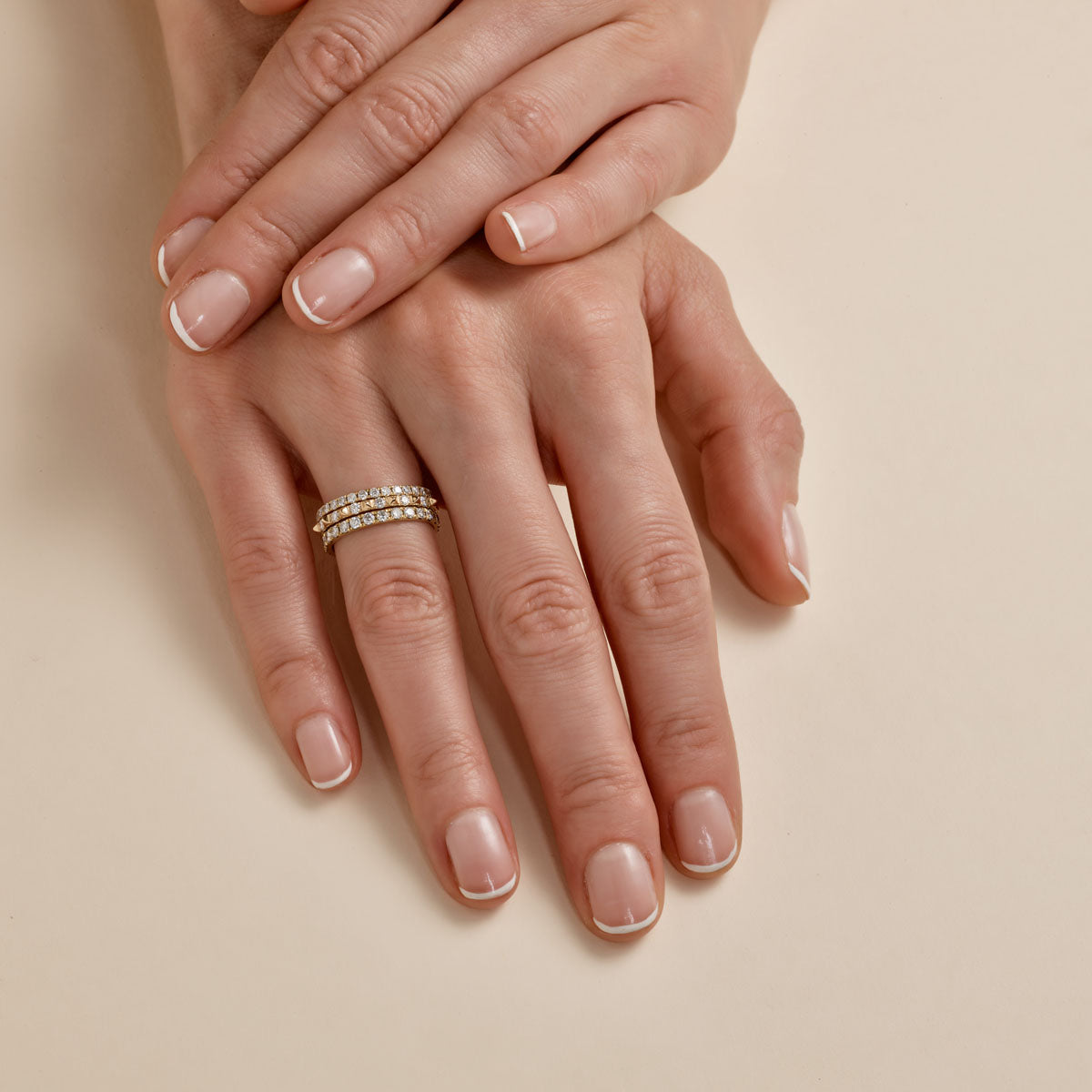 multiple white diamond rings stacked on womans finger