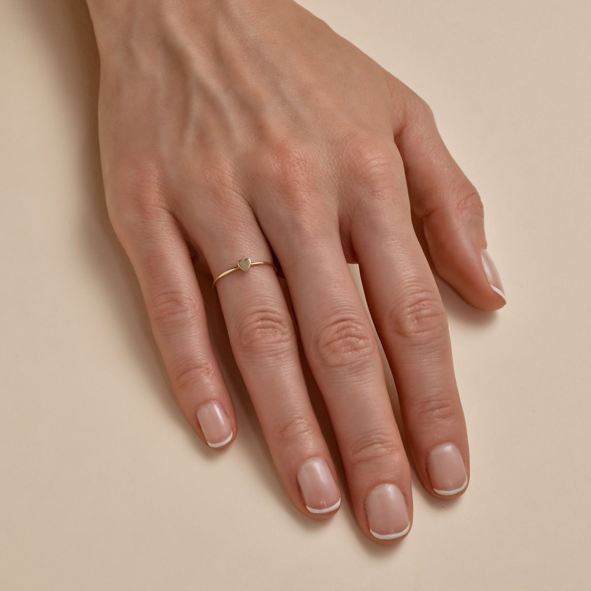tiny diamond heart ring on womans finger