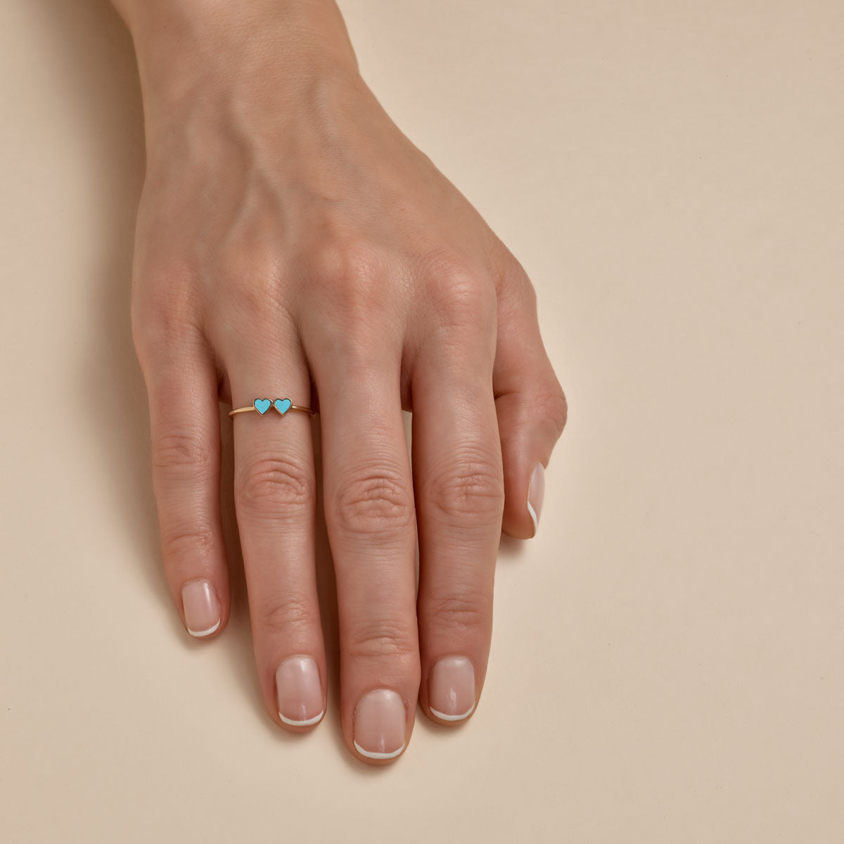 turquoise double heart gold ring on womans finger